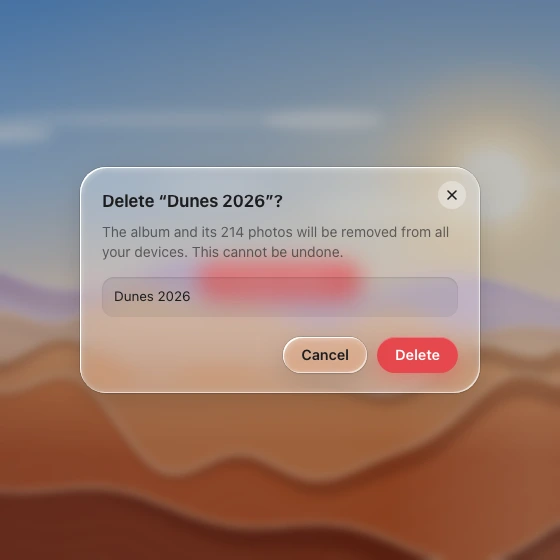 A frosted confirmation dialog over a dimmed, blurred dune scene, with a filled confirm field, a glass Cancel and a solid red Delete.